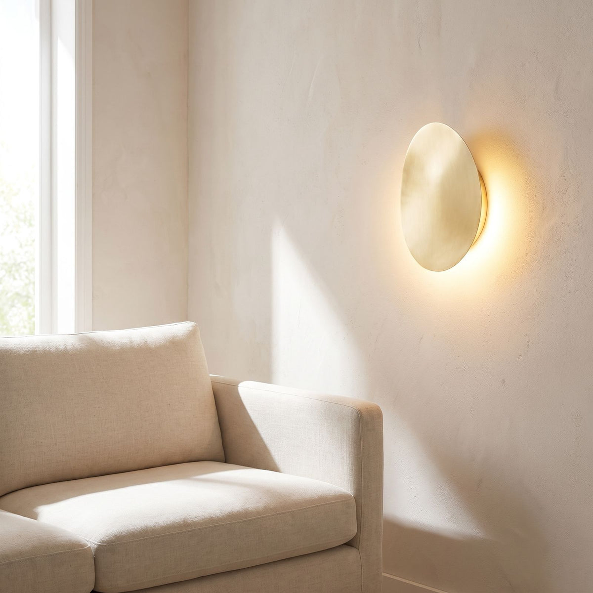 Tilted pebble backlit LED wall light beside a living room sofa in daylight
