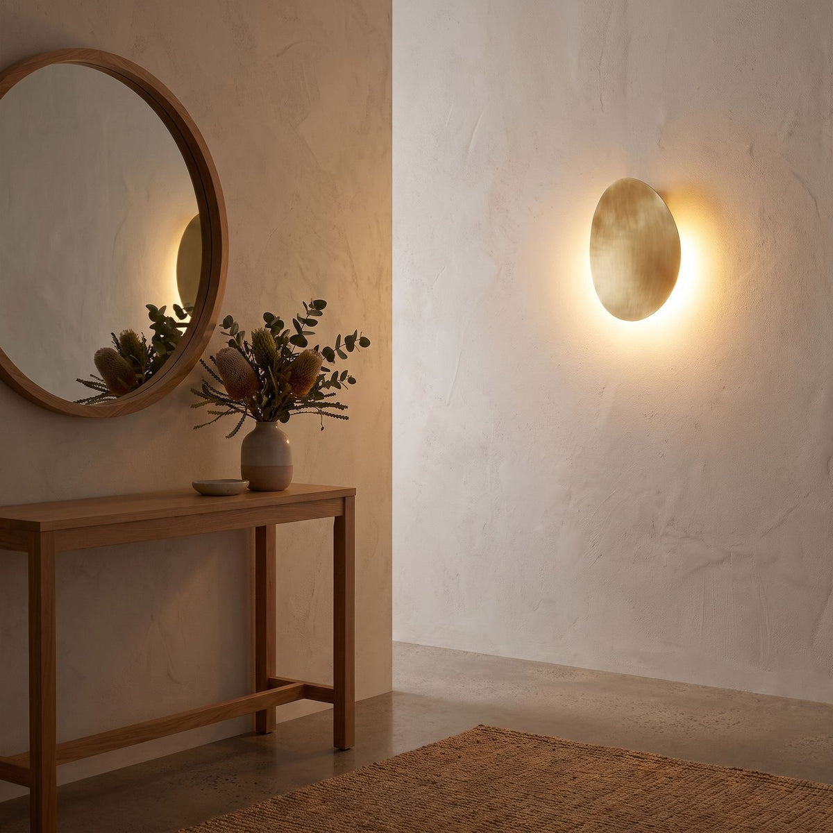 Tilted pebble backlit LED wall light beside a round mirror in an entry hall at night
