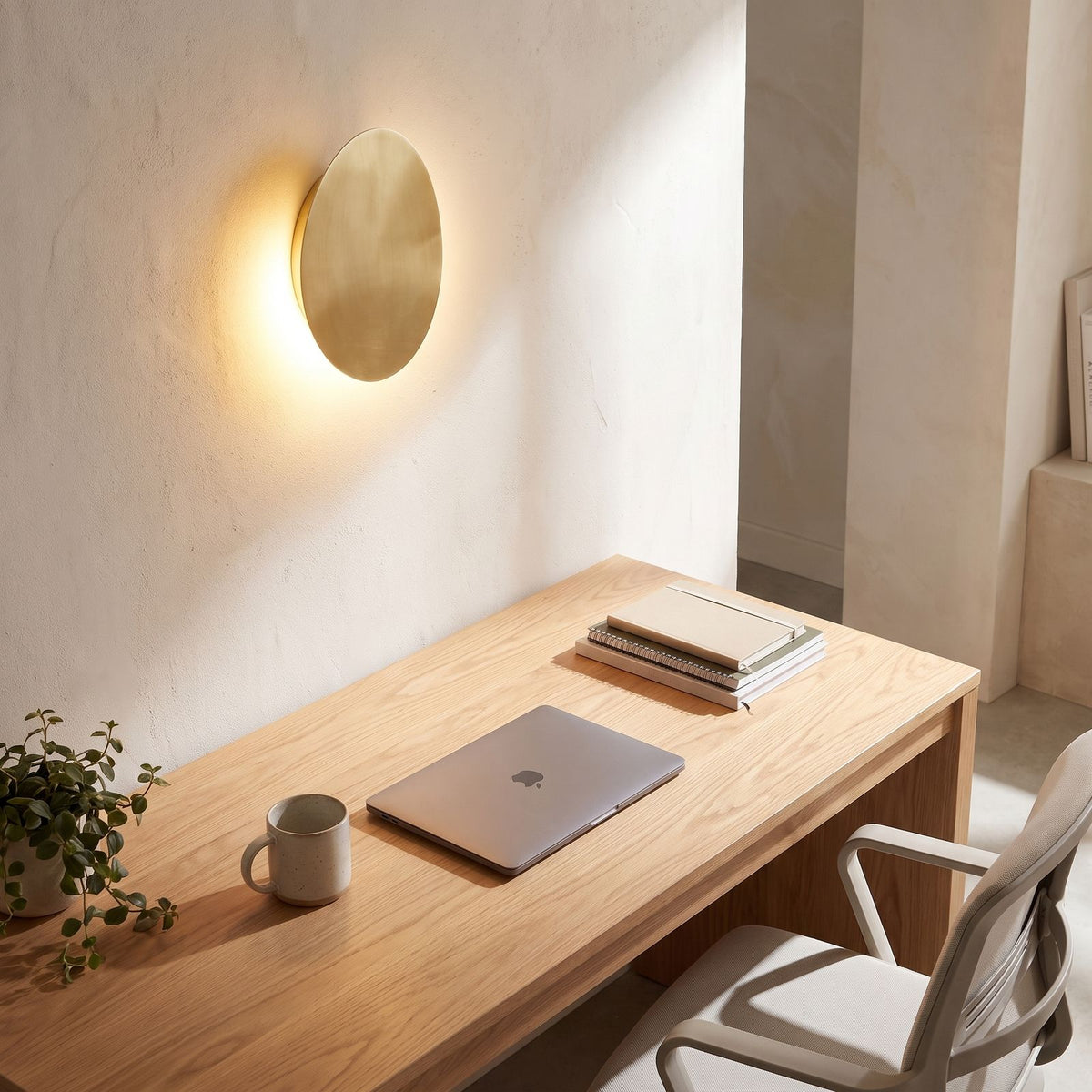 Tilted pebble backlit LED wall light above a home office desk in daylight