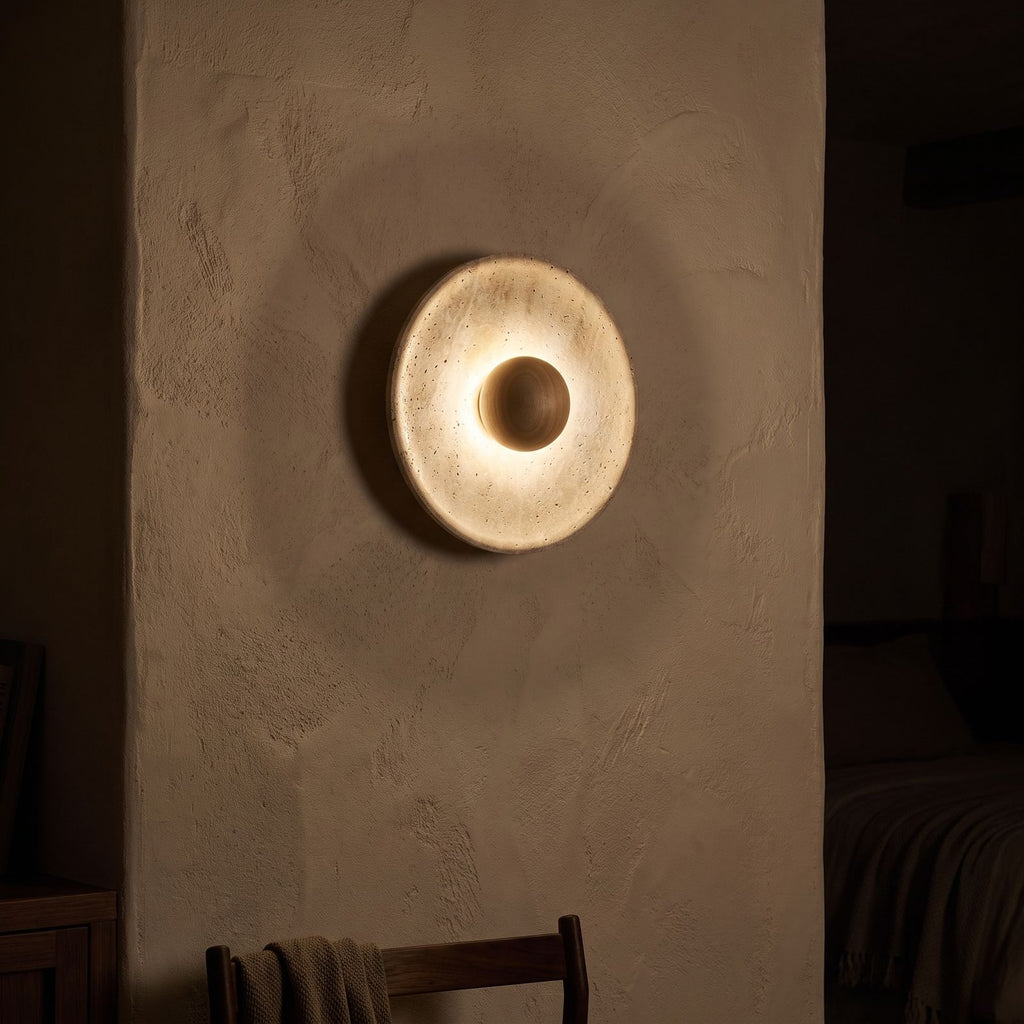 Timber Shade Travertine Wall Light glowing on a plaster wall at night