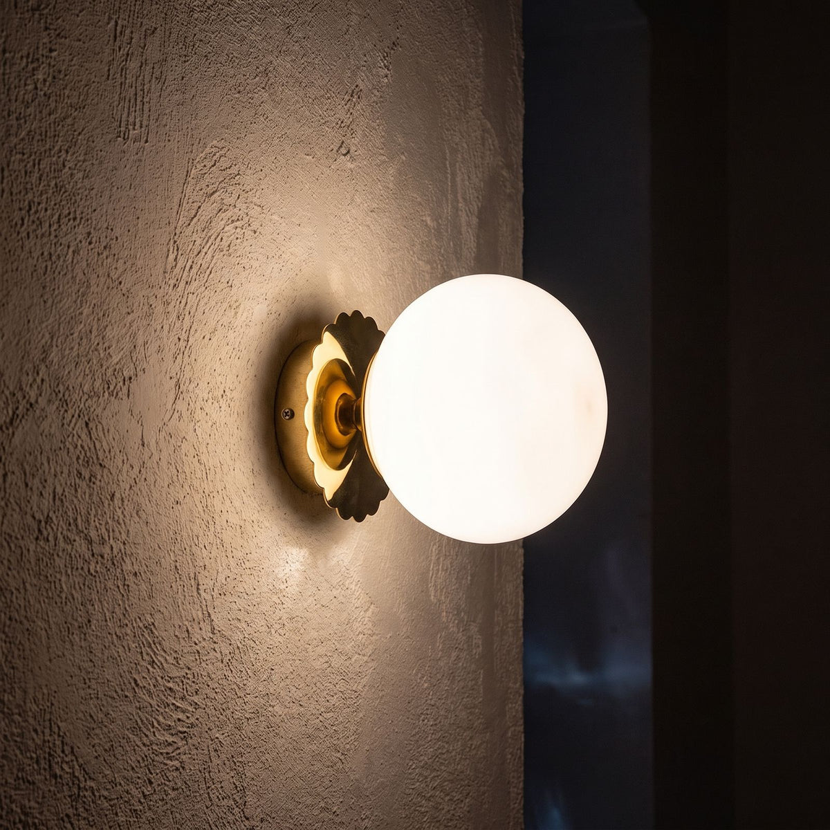 Tinted Glass Ball Up and Down Wall Light glowing on a plaster wall at night