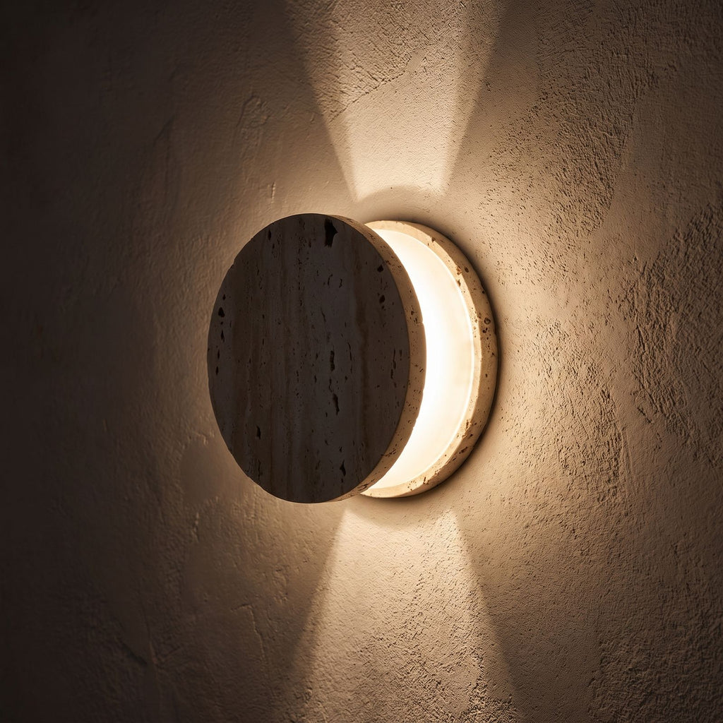 Travertine and Frosted Glass Up Down Wall Light glowing on a plaster wall at night