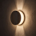 Travertine and Frosted Glass Up Down Wall Light glowing on a plaster wall at night