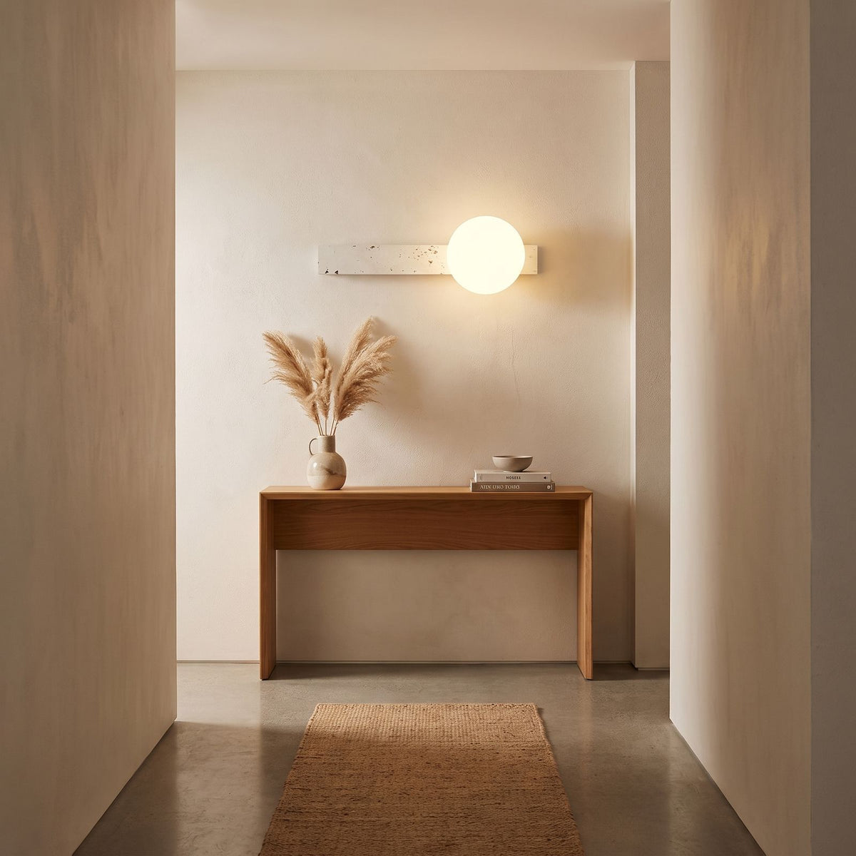 Travertine Bar and White Globe Wall Light in a hallway above a timber console