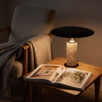 Travertine Column Wide Disc Shade Table Lamp beside an armchair in a reading corner at night