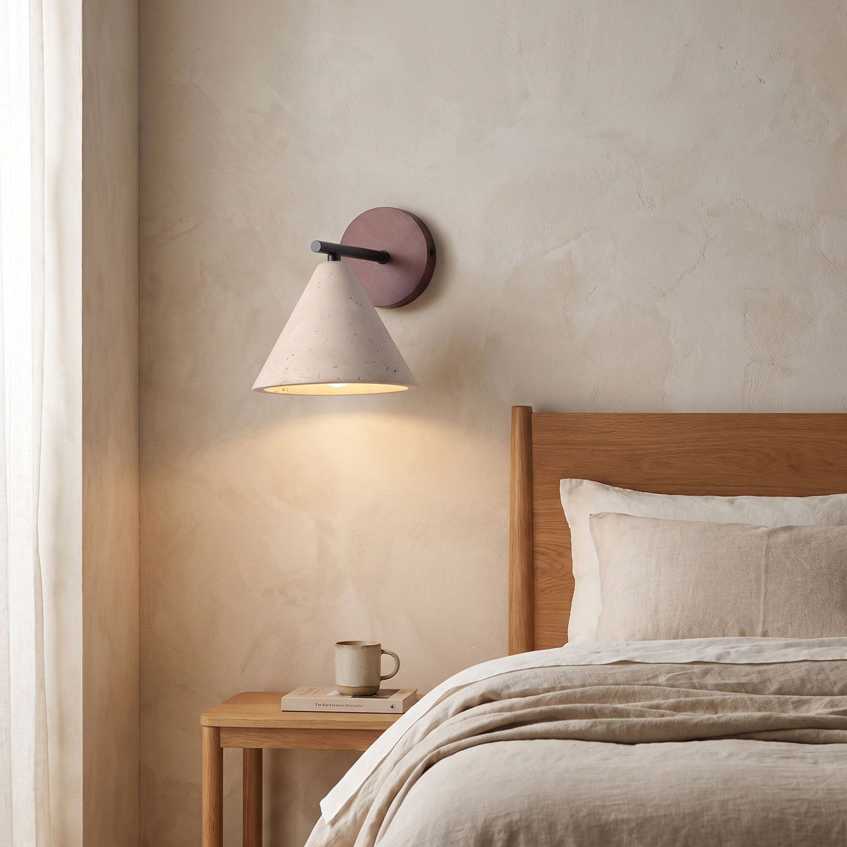 Travertine Cone and Wood Wall Light on a bedroom wall beside the bed