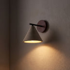 Travertine Cone and Wood Wall Light glowing on a plaster wall at night