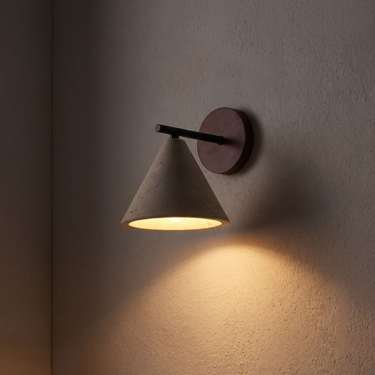 Travertine Cone and Wood Wall Light glowing on a plaster wall at night