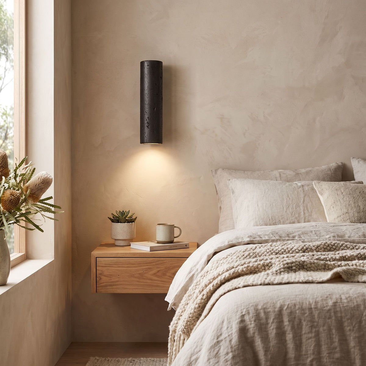 Travertine Cylinder Integrated LED Wall Light on a bedroom wall beside the bed