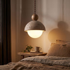 Travertine dome and glass globe pendant light over a bedside table at night