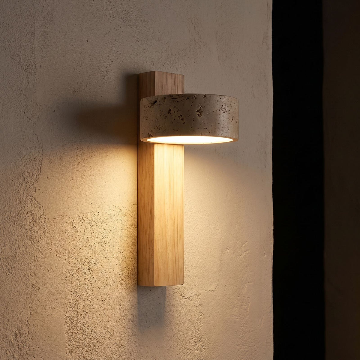 Travertine Drum and Wood Post Swivel Wall Light glowing on a plaster wall at night