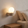 Travertine Ledge and Frosted Glass Orb Wall Sconce beside a bed