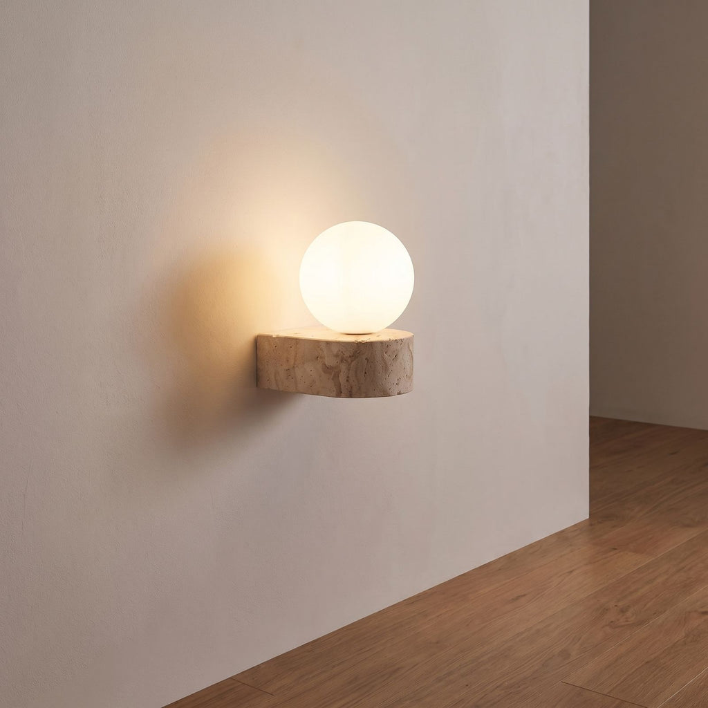 Travertine ledge and frosted glass orb wall sconce on a hallway wall