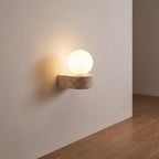 Travertine ledge and frosted glass orb wall sconce on a hallway wall