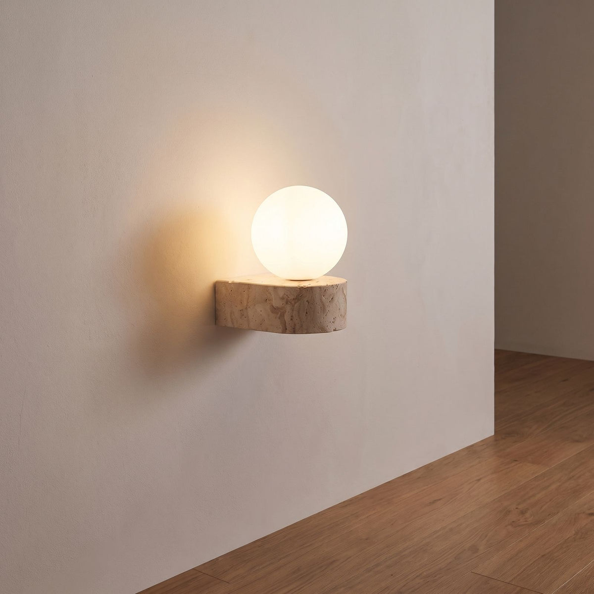 Travertine ledge and frosted glass orb wall sconce on a hallway wall