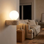 Travertine ledge and frosted glass orb wall sconce beside a living room sofa at night