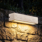 Travertine Look Resin Linear Up Down Outdoor Wall Light glowing on a garden wall at night