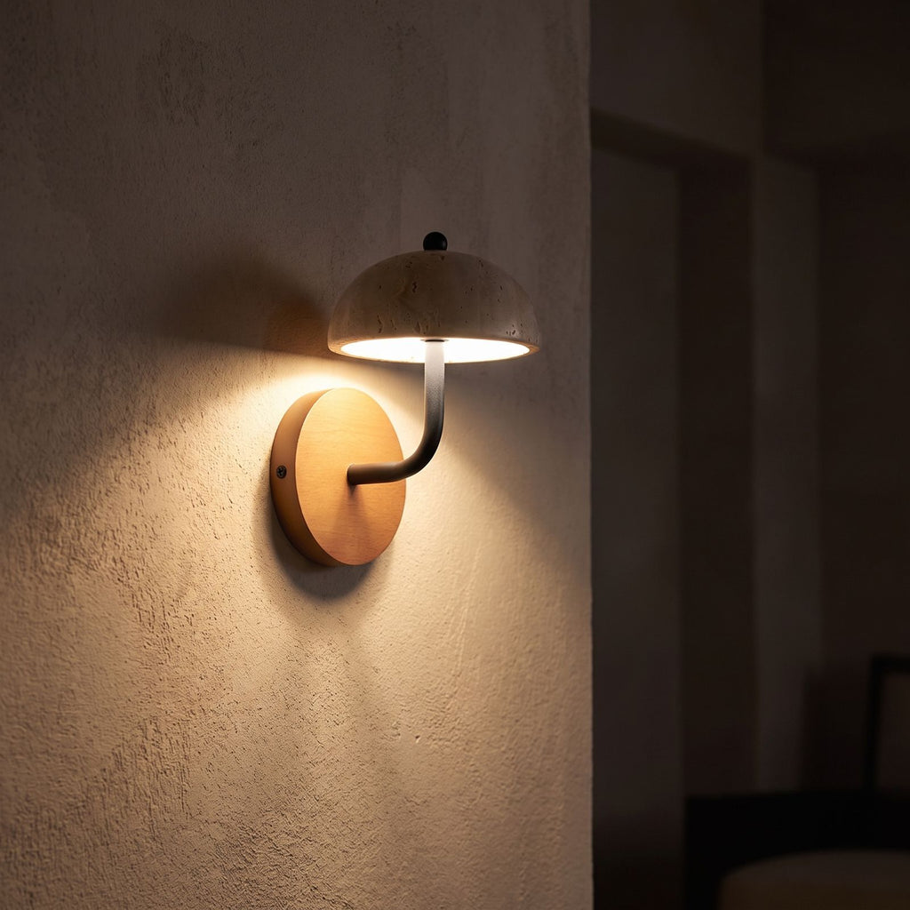 Travertine Mushroom Dome Bedside Wall Light glowing on a plaster wall at night