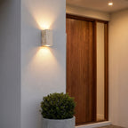 Travertine Stone Outdoor Up Down Wall Light beside a front door at dusk