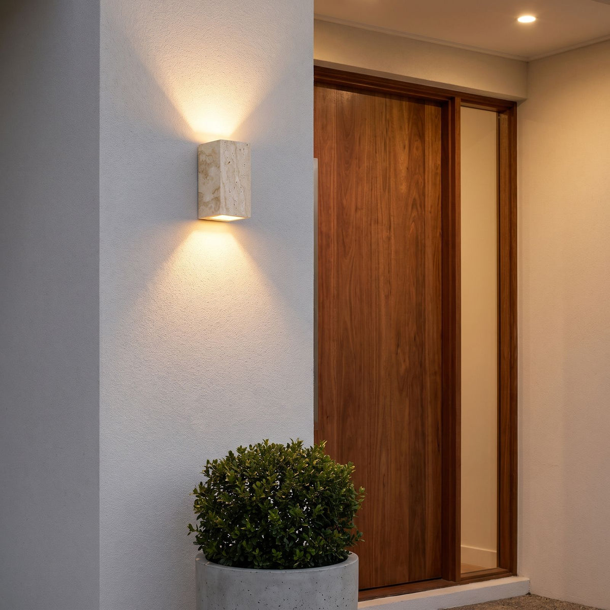 Travertine Stone Outdoor Up Down Wall Light beside a front door at dusk