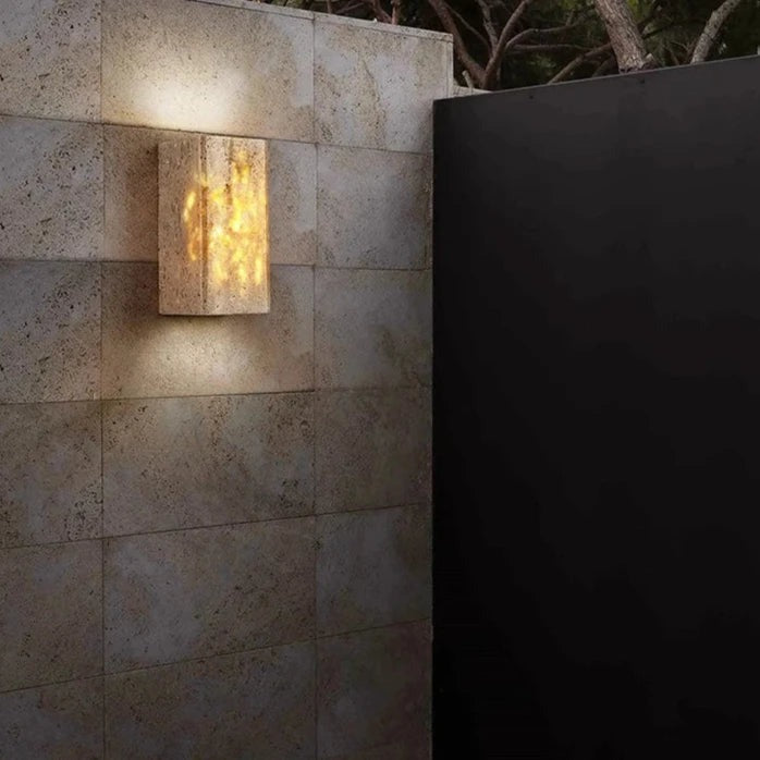 Travertine outdoor wall light glowing on a stone clad wall