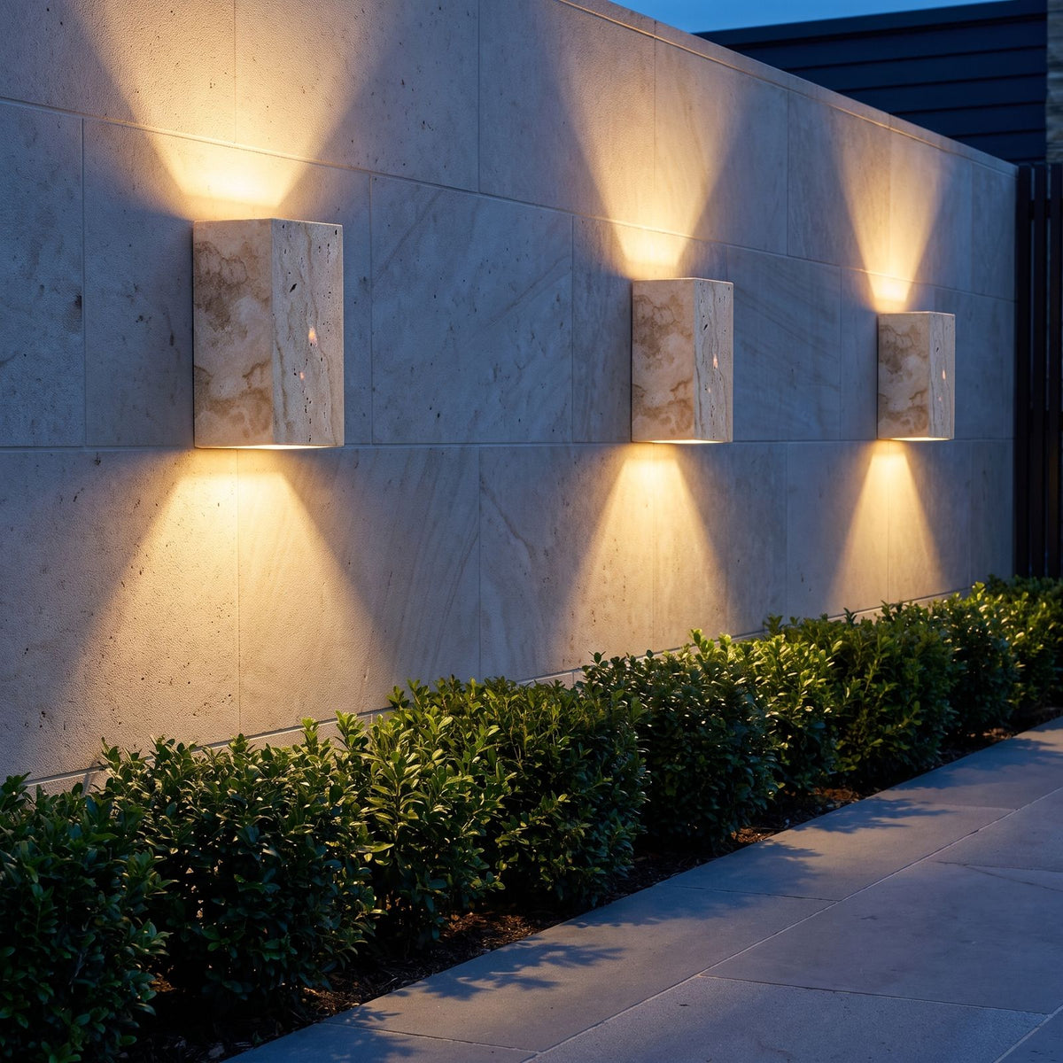 Three Travertine Stone Outdoor Up Down Wall Lights along a stone garden wall