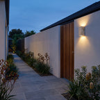 Travertine Stone Outdoor Up Down Wall Light on a garden path wall at dusk