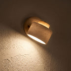 Travertine Stone Reading Wall Light glowing on a plaster wall at night