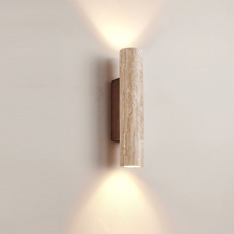Close view of a travertine tube wall light glowing up and down