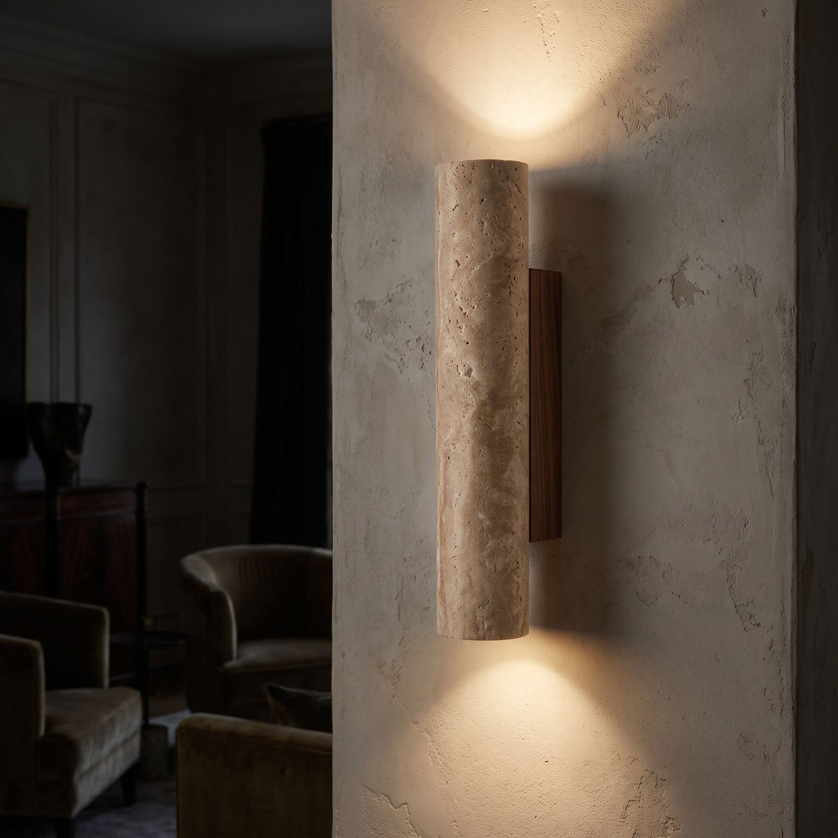 Travertine Tube Up Down Wall Light on a limewashed wall at night