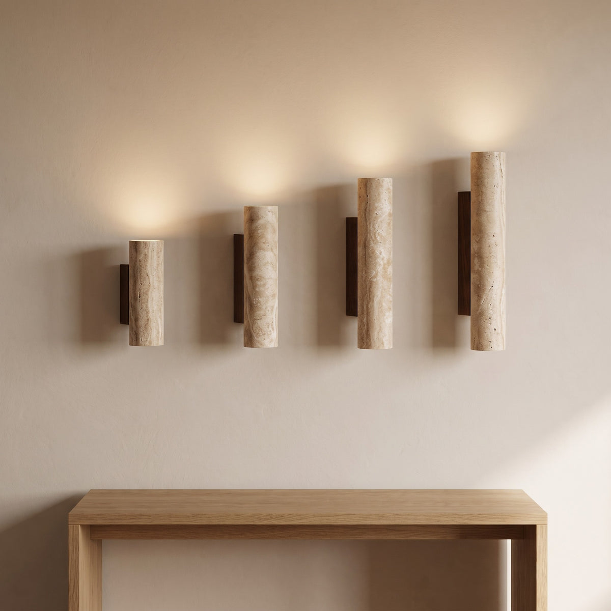 Four travertine tube wall lights in 16, 23, 28 and 32 cm lengths mounted in a row on a plaster wall