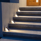 Triangular solar step lights on concrete front entry steps at dusk