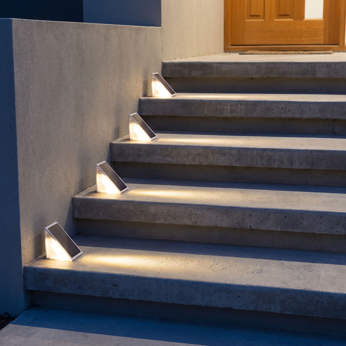 Triangular solar step lights on concrete front entry steps at dusk