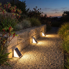 Triangular solar lights along a garden path and stone wall