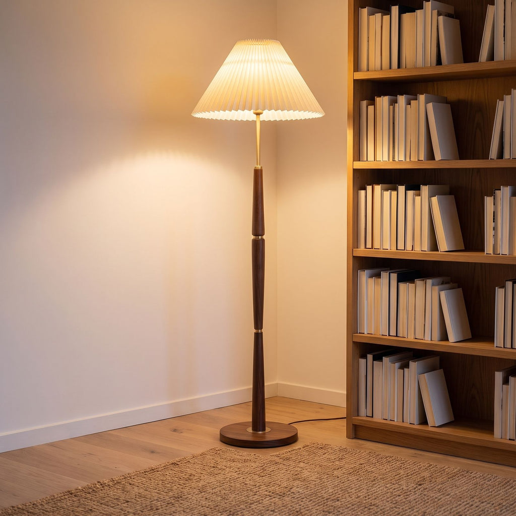 Turned wood floor lamp with pleated shade in a reading corner beside a bookshelf