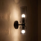 Twin Coloured Glass Shade Wall Light glowing on a plaster wall at night