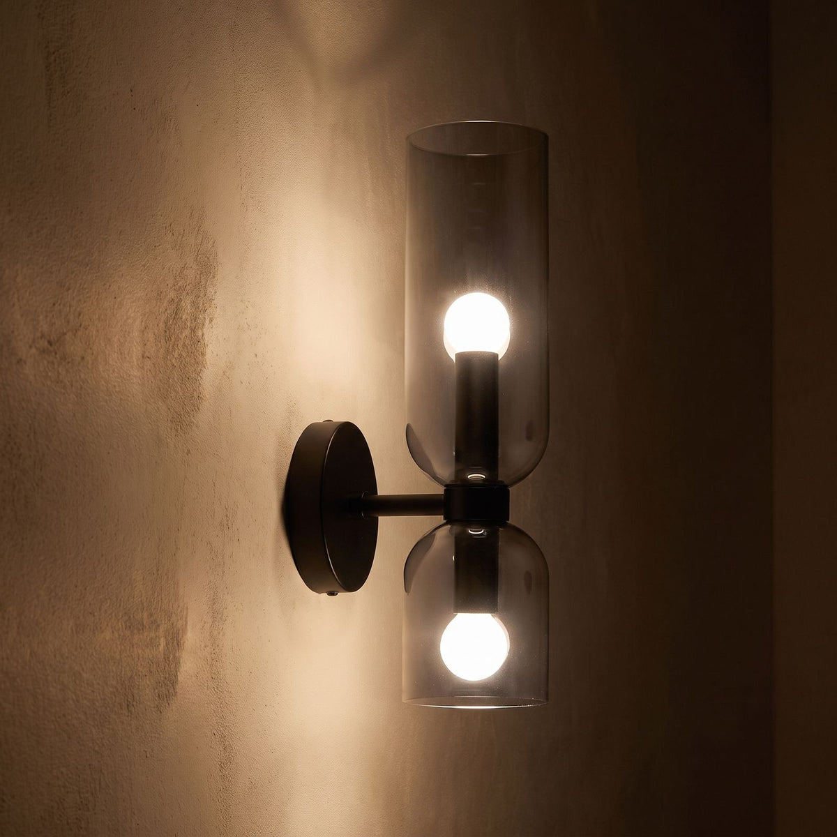 Twin Coloured Glass Shade Wall Light glowing on a plaster wall at night