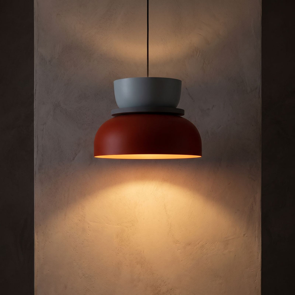 Two-Tone Stacked Metal Bowl Pendant Light glowing against a plaster wall at night