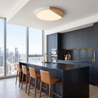 White ultra thin LED oyster ceiling light above a dark stone island in a penthouse kitchen