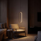 Vertical oval ring LED pendant light over a reading armchair at night