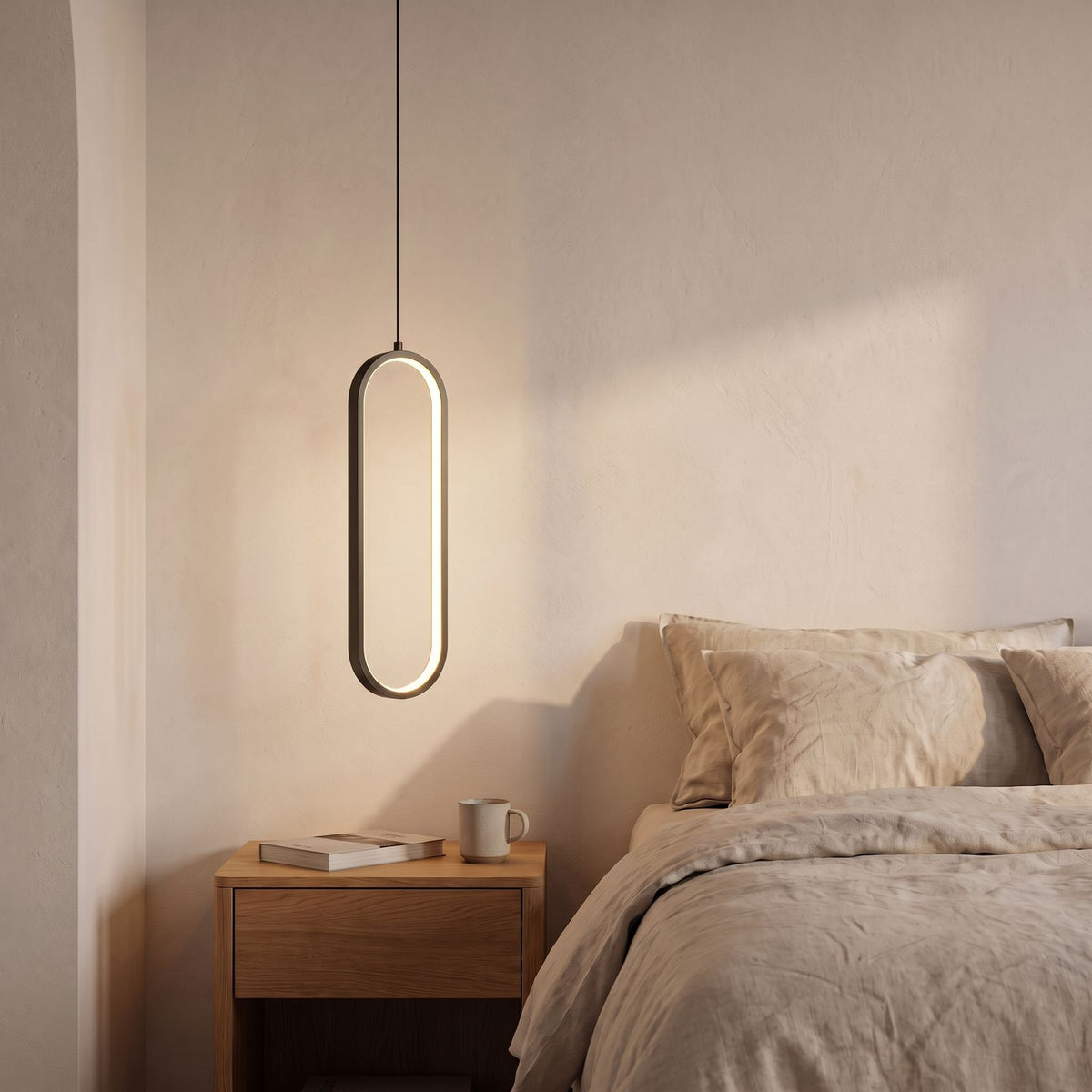 Vertical Oval Ring LED Pendant Light in black beside a bed