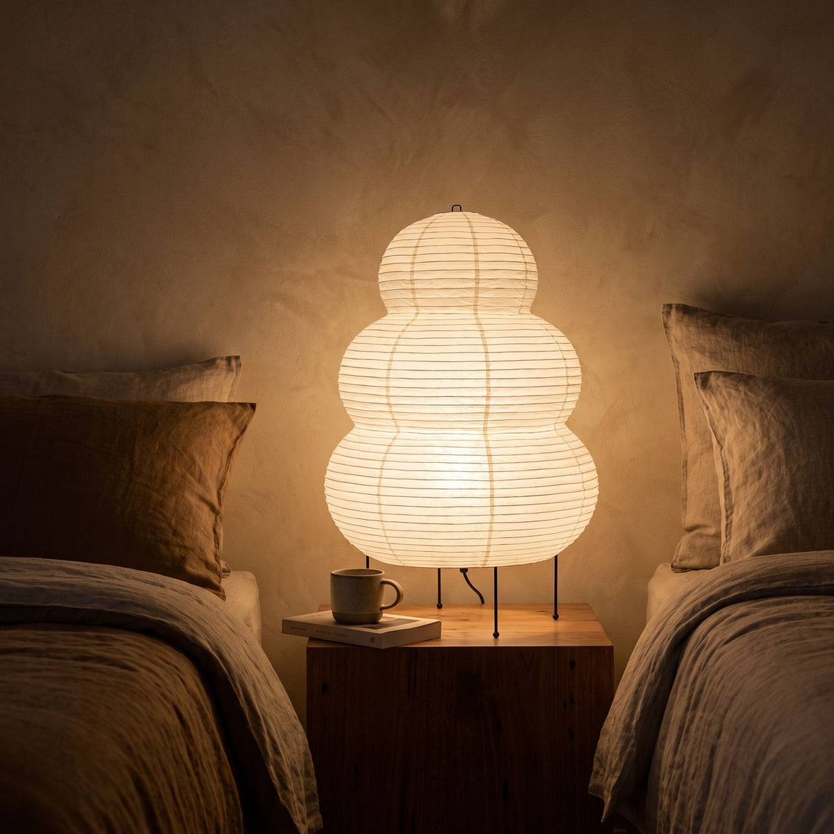 Wabi-Sabi Rice Paper Tripod Table Lamp glowing on a bedside table at night