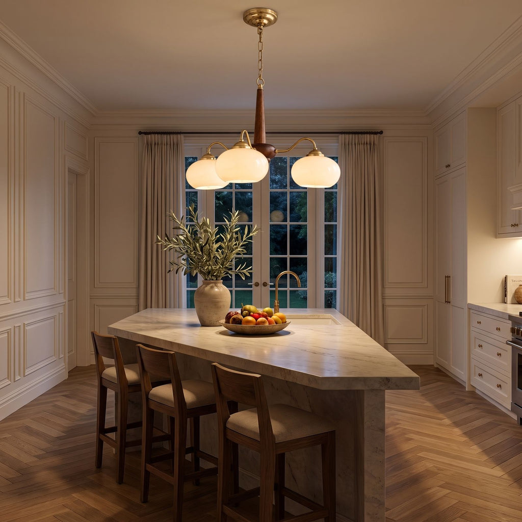 Walnut Wood and Brass Arm Glass Shade Chandelier above a kitchen island at night
