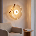 Wavy art glass disc wall light above an armchair in a reading corner