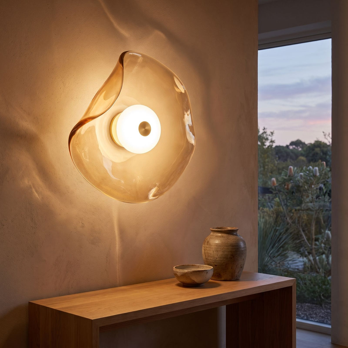 Wavy art glass disc wall light above an entry console