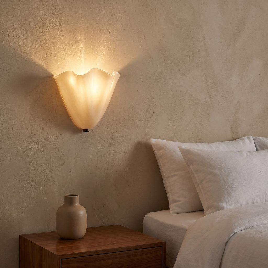 Wavy Beige Glass Shell Wall Light beside a bed at night