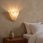 Wavy Beige Glass Shell Wall Light beside a bed at night