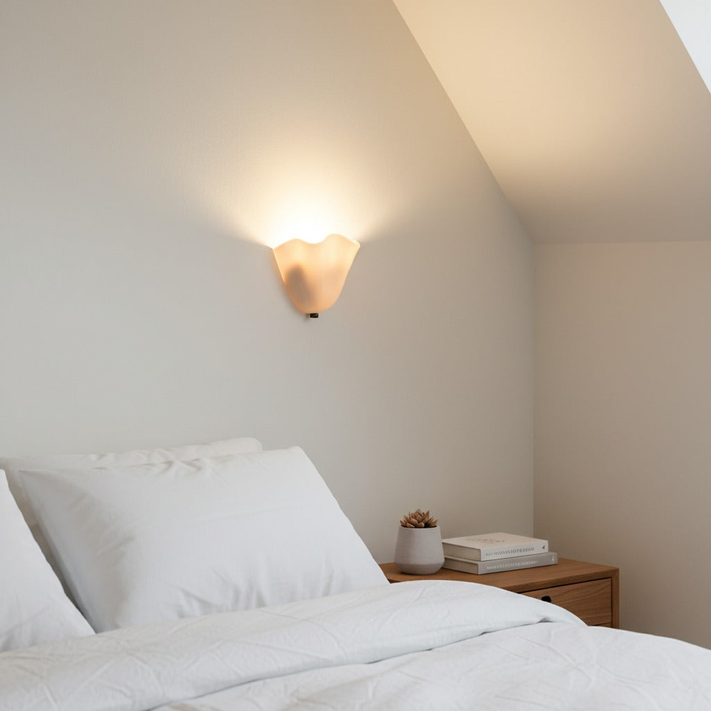 Glass shell wall light above a bed in a light bedroom