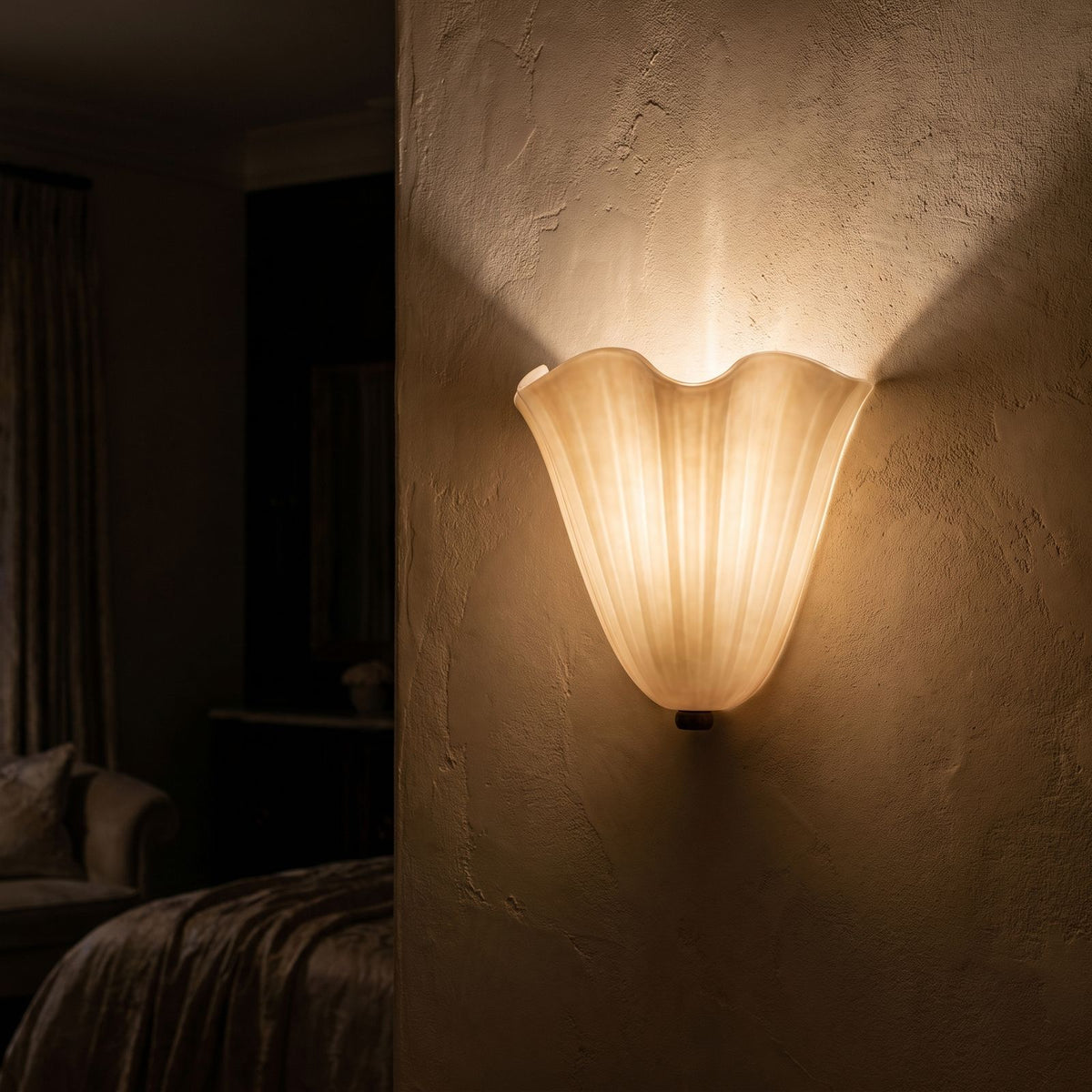 Wavy Beige Glass Shell Wall Light on a limewashed wall at night