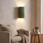 Wavy ribbed resin up down wall light above an armchair in a reading corner